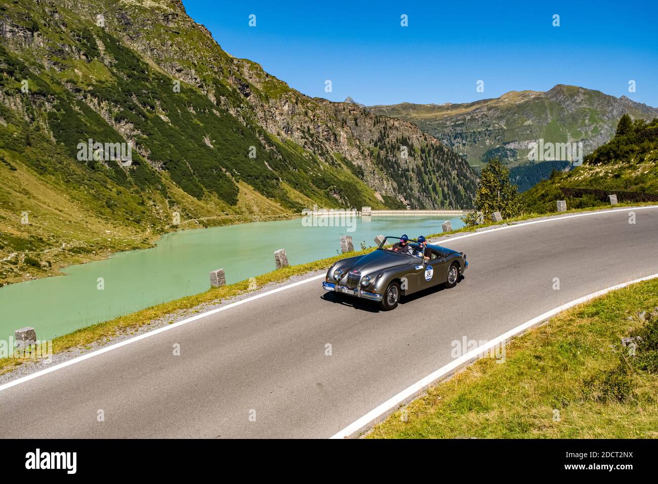 Ein Oldtimer Jaguar XK 150 Cabrio fährt bei der Arlberg Classic Car Rally an einem See vorbei auf der Silvretta Hochalpenstraße. Stockfoto