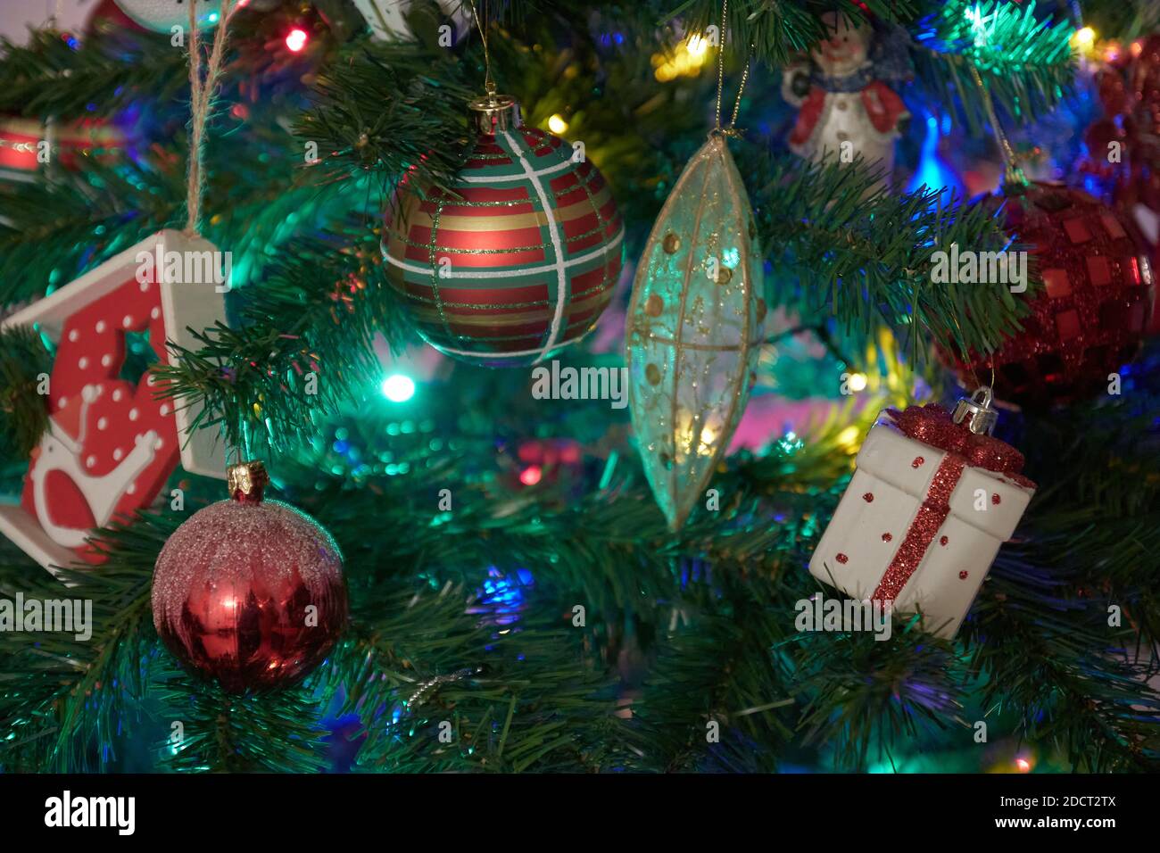 Weihnachtsschmuck auf Weihnachtsbaum mit hängenden Kugeln und Ornamenten und Bokeh Hintergrund. Stockfoto