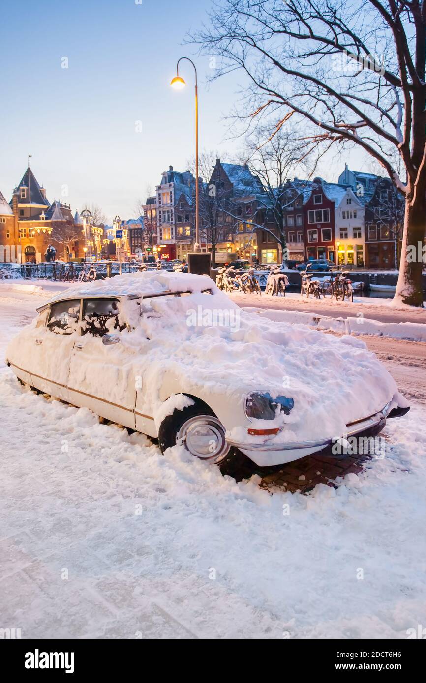 Klassisches französisches Auto bedeckt mit Schnee an einem Wintertag während Sonnenuntergang in Amsterdam, Niederlande Stockfoto