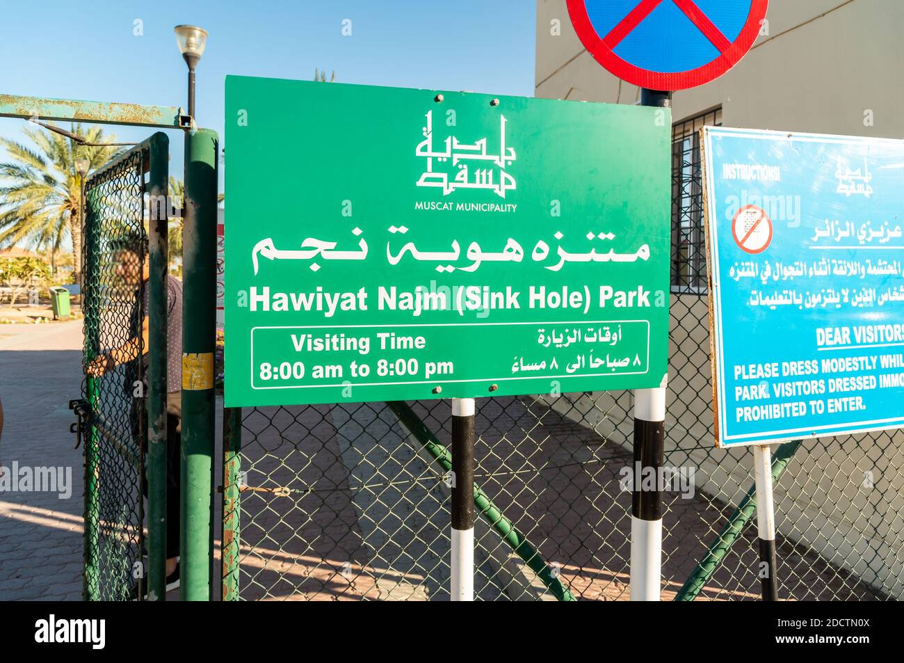 Schild mit Besuchszeit alle ingresso di Hawiyat Najm (Sink Hole) Park, in englischer und arabischer Sprache, Muscat Gemeinde, Sultanat von Oman. Stockfoto