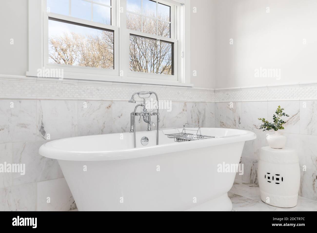 Ein luxuriöses Badezimmer mit einer Victoria + Albert Badewanne und Chrom Wasserhahn umgeben von Marmorfliesen auf dem Boden und an den Wänden. Stockfoto