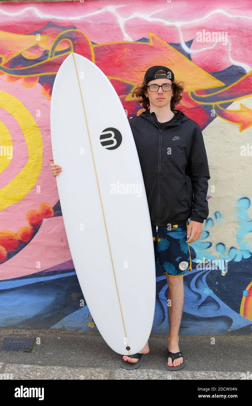 England, Cornwall, Newquay, Surfer mit Surfbrett vor farbenfroher Wand. Stockfoto