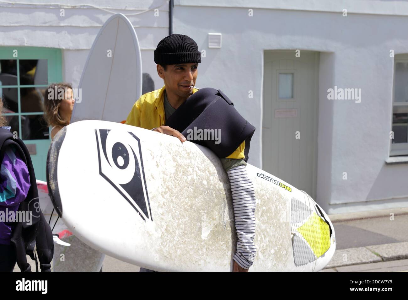 Surfer, die ihre Surfbretter tragen, wandern im Stadtzentrum von Newquay, Cornwall. Stockfoto