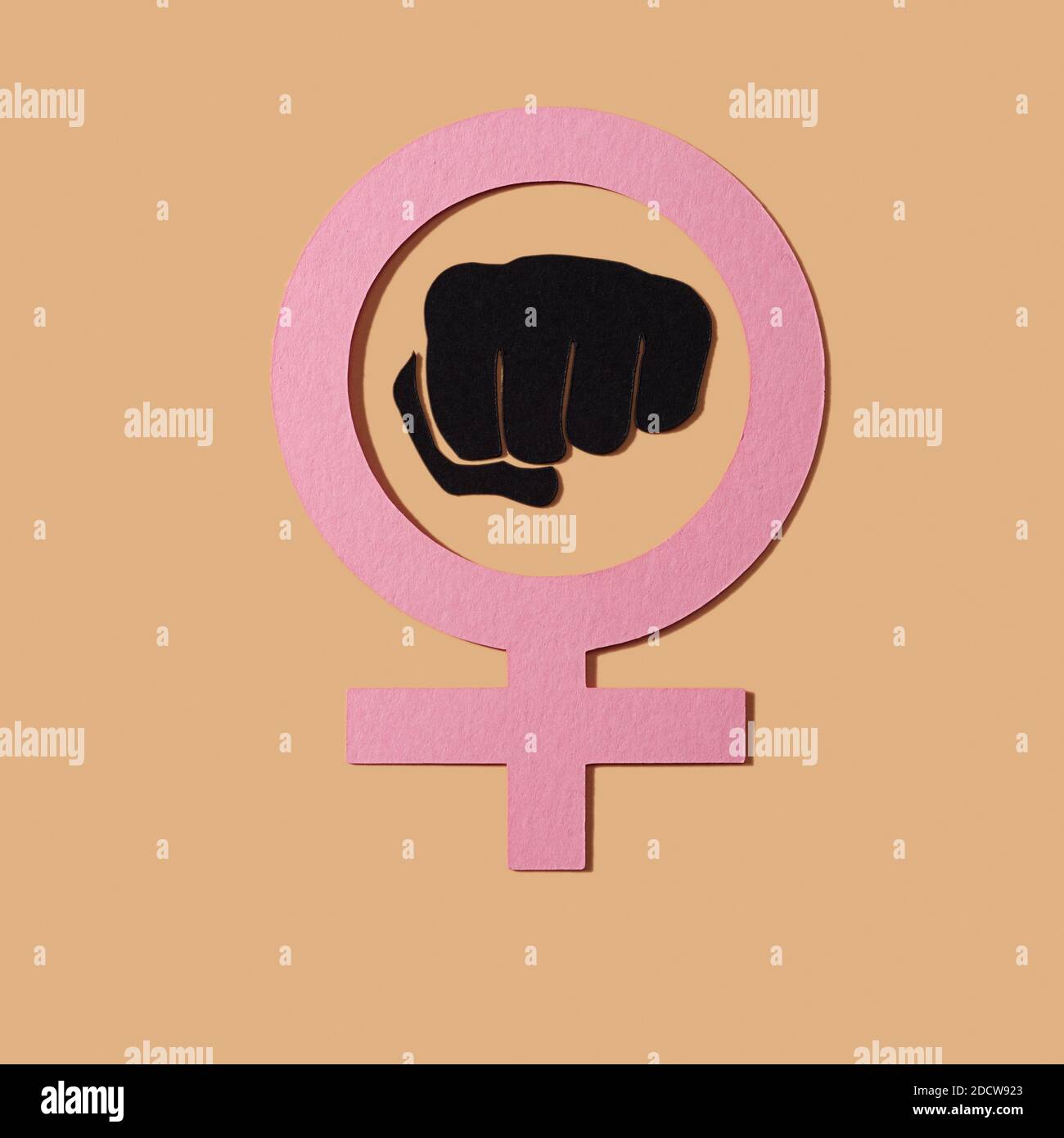 Das Frauen-Power-Symbol, eine erhobene Faust in einem weiblichen Geschlecht-Symbol, mit Ausschnitten aus Papier in verschiedenen Farben auf einem lachsrosa Hintergrund gemacht Stockfoto