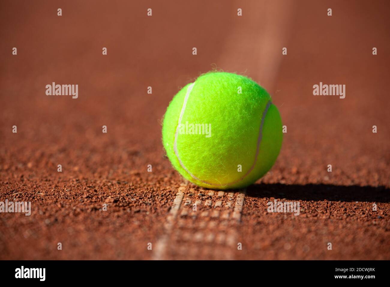 Tennisball auf der weißen Linie eines Tonfeldes, Nahaufnahme Stockfoto