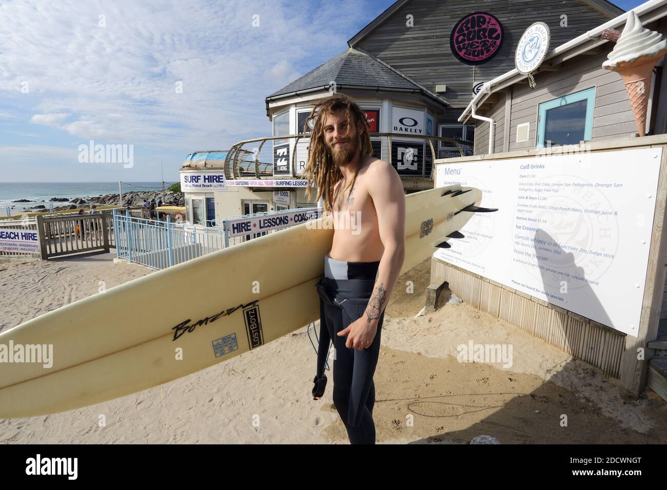 Portrait des glücklichen Surfers mit Dreadlocks und Surfbrett am Fistral Beach in Newquay, Cornwall, England Stockfoto