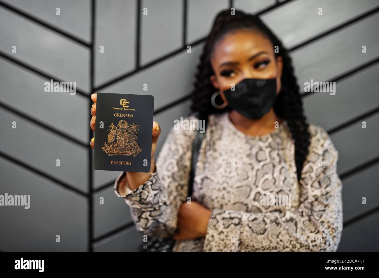 afroamerikanische Frau trägt schwarze Gesichtsmaske zeigen Grenada Pass in der Hand. Coronavirus in Amerika Land, Grenze Schließung und Quarantäne, Virus aus Stockfoto