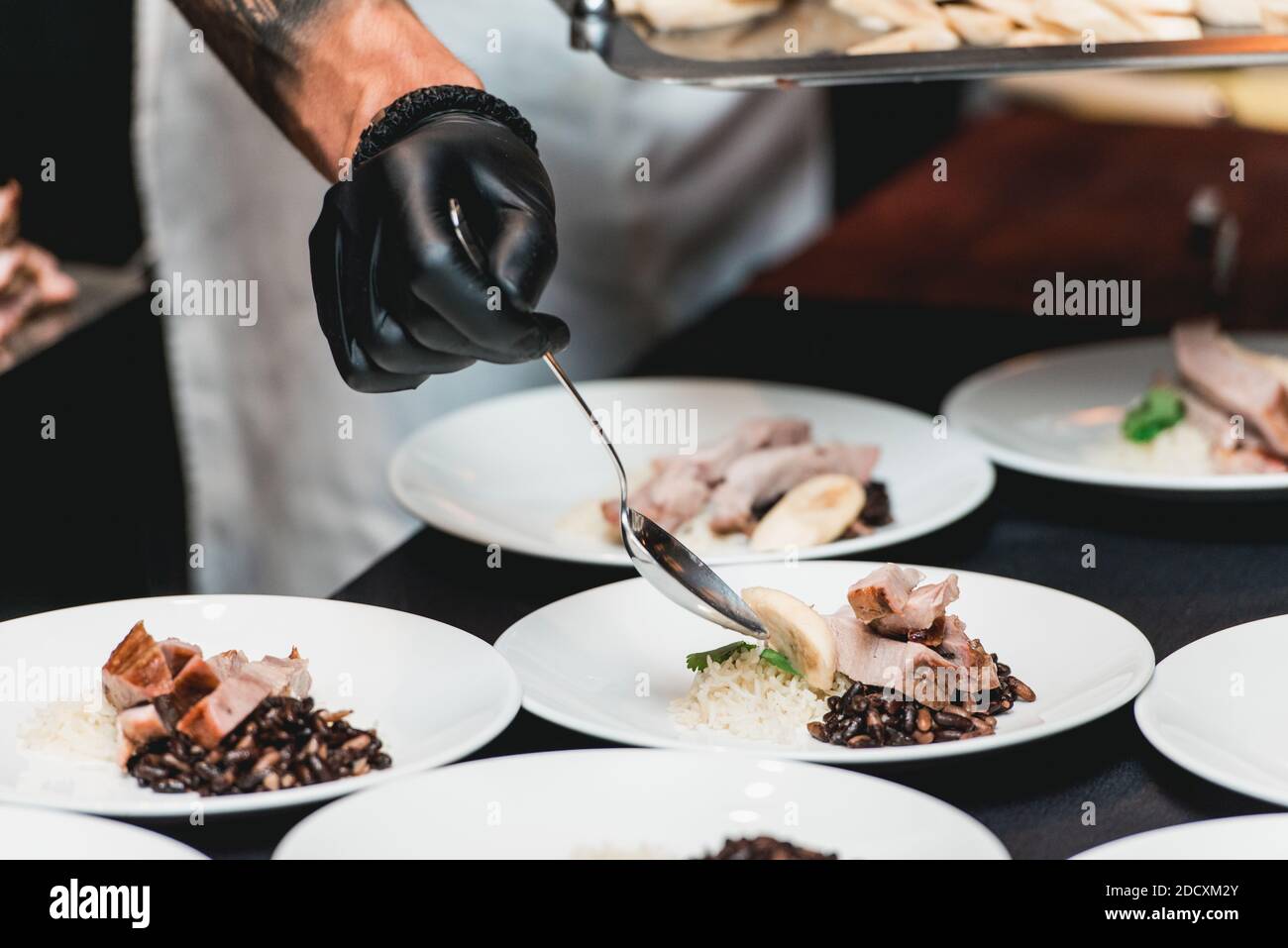 Kubanische Rindfleisch-Picadillo serviert mit weißem Reis und schwarzen Bohnen. Serviert auf einem Tisch mit schwarzer Tischdecke. Stockfoto