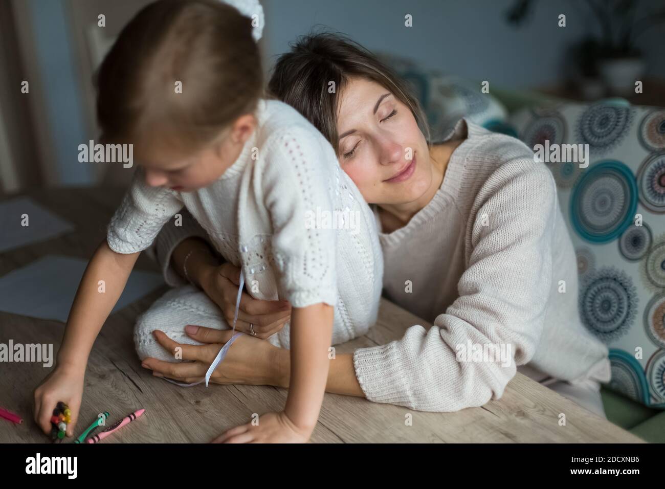 Mutter mit Tochter, elterlicher Kontakt. Mädchen auf dem Tisch sitzen. Stockfoto