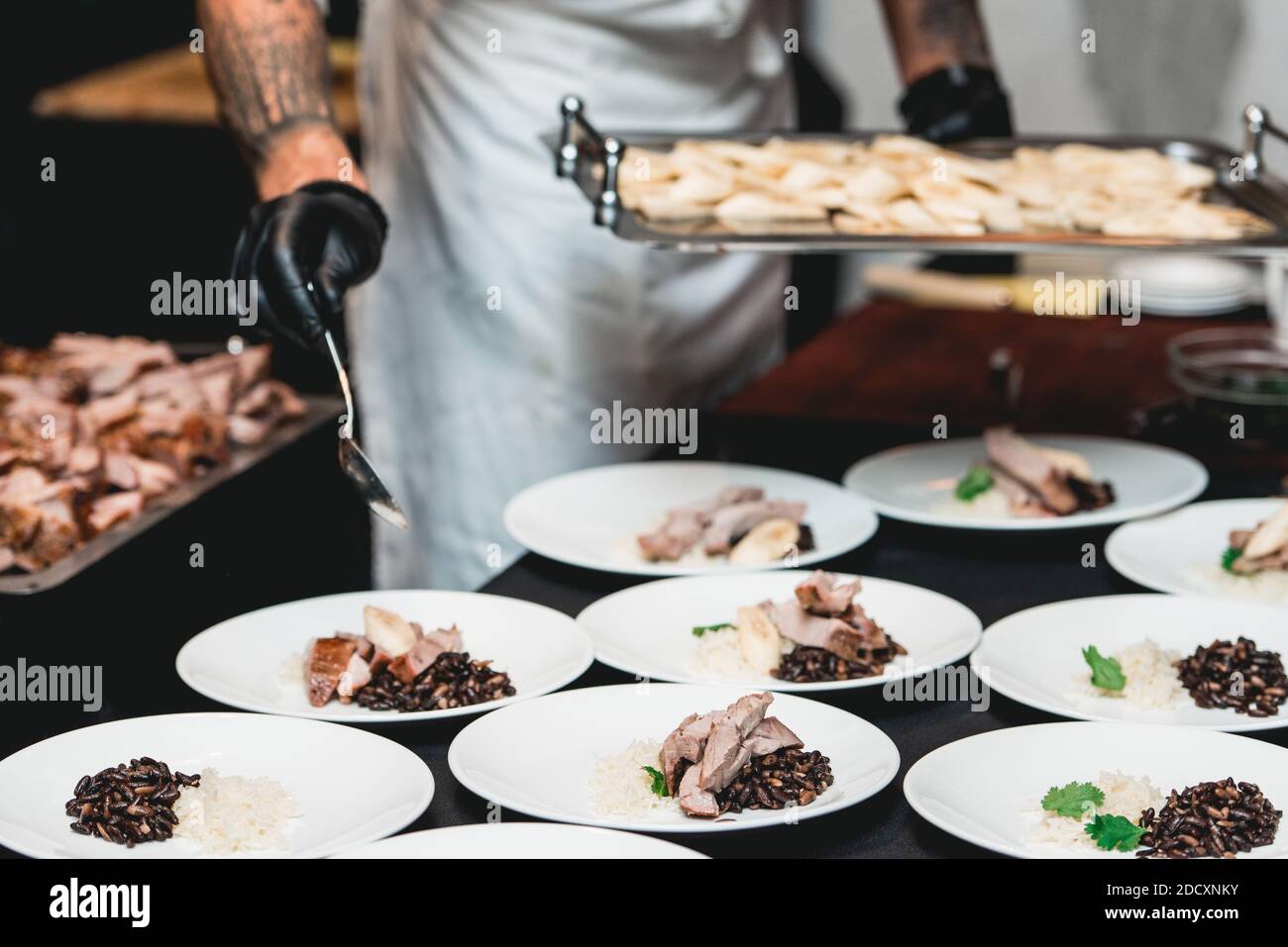 Kubanische Rindfleisch-Picadillo serviert mit weißem Reis und schwarzen Bohnen. Serviert auf einem Tisch mit schwarzer Tischdecke. Stockfoto