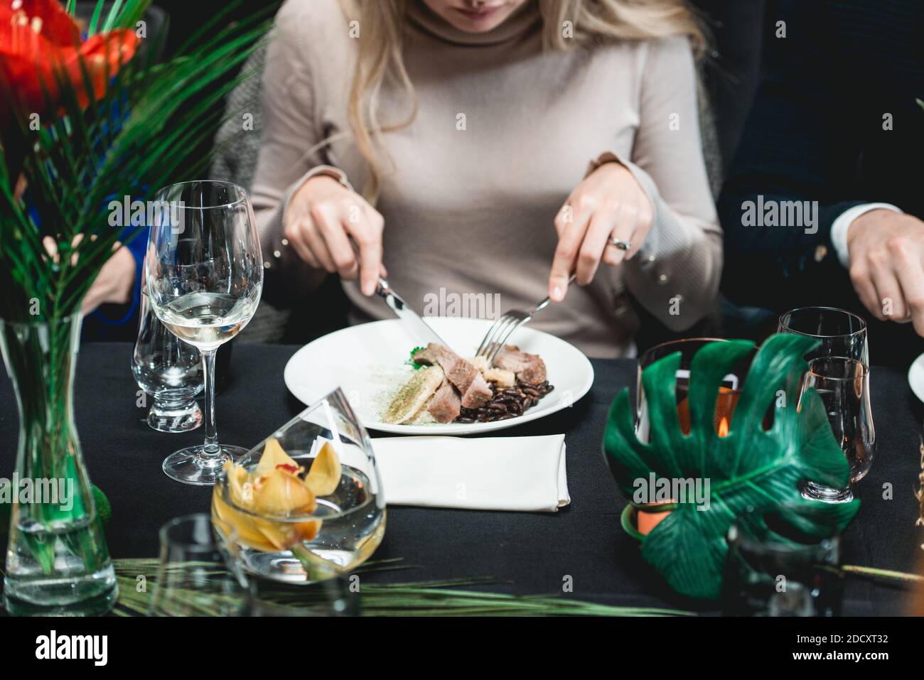 Frau in einem Restaurant essen kubanischen Stil Rindfleisch Picadillo serviert mit weißem Reis und schwarzen Bohnen. Serviert auf einem Tisch mit schwarzer Tischdecke. Stockfoto