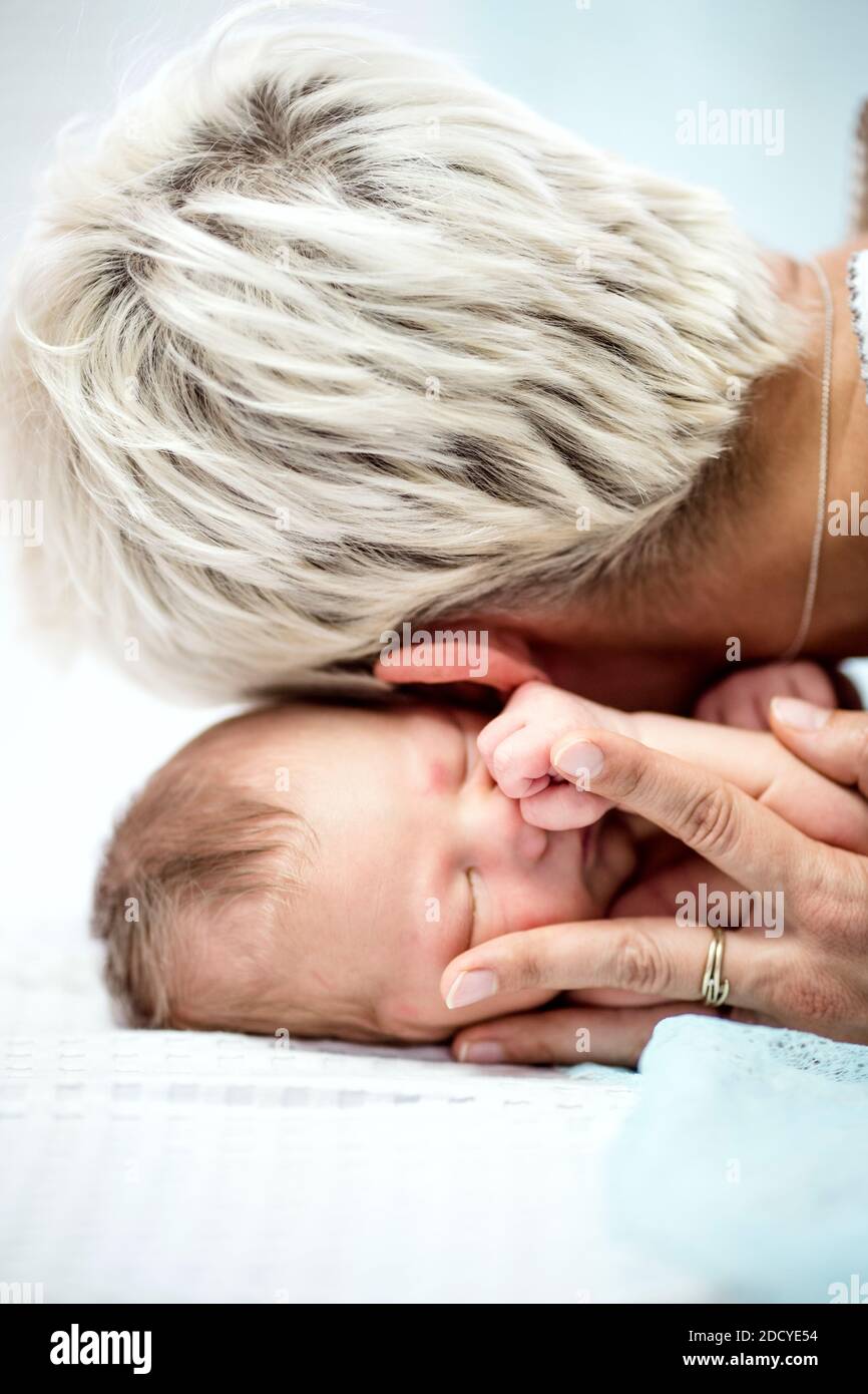 Intimes Porträt des schlafenden, neugeborenen Jungen umarmt von seiner Mutter Stockfoto