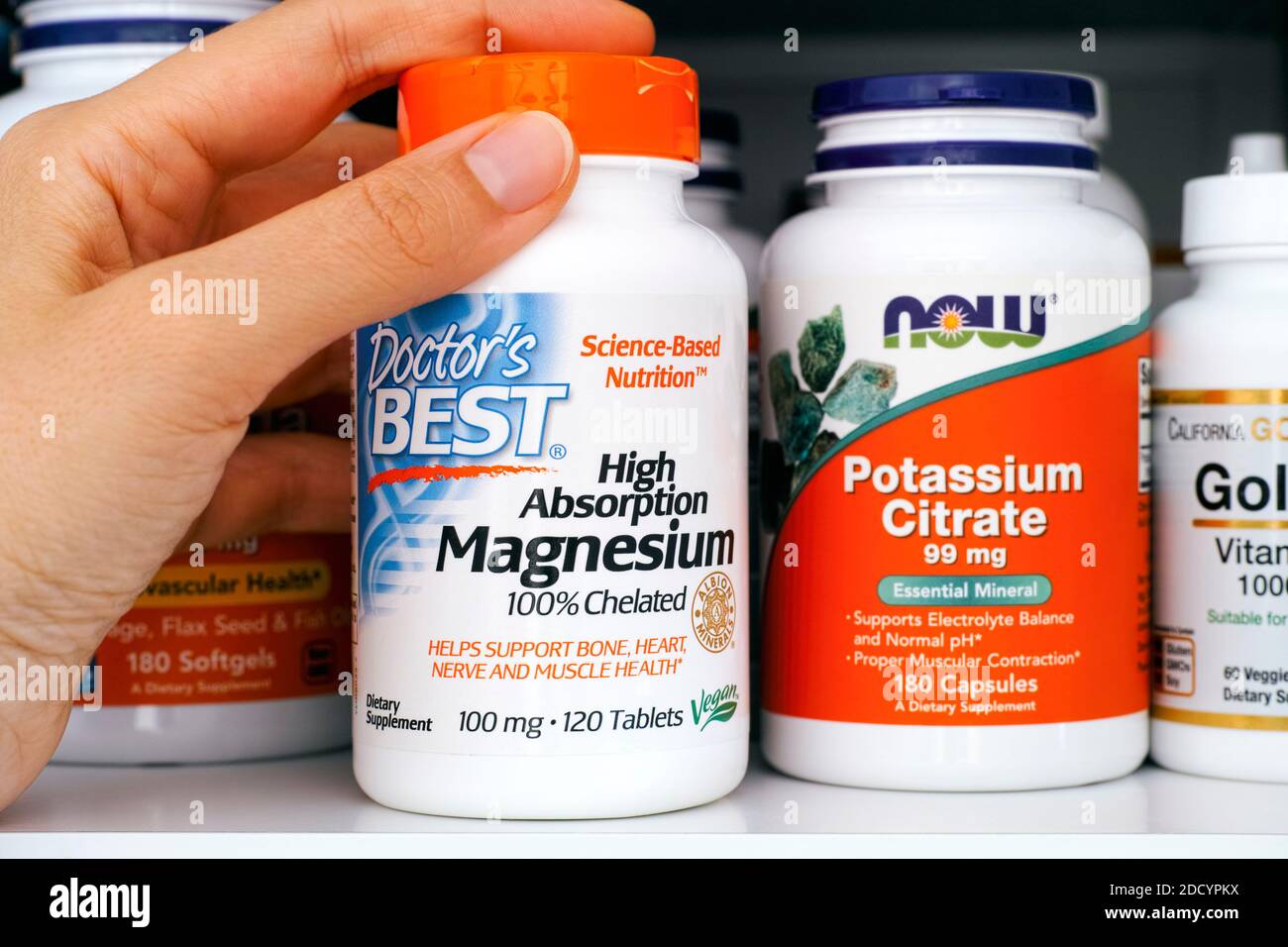 Tambow, Russische Föderation - 28. Oktober 2020 Frau, die eine Flasche hochabsorbierenden Magnesiums herausnimmt von Doctors Best aus einem Schrank Stockfoto