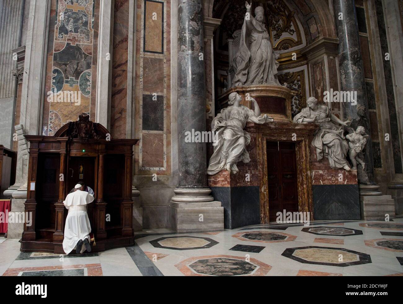 Papst Franziskus kniet in der Beichte, nachdem er am 9. März 2018 in der Petersbasilika im Vatikan eine Bußfeier gefeiert hat. Rechts: Das Grab von Papst Benedikt XIV. Der Bußgottesdienst im Petersdom war der Beginn der weltweiten Feier „24 Stunden für den Herrn“, einer Zeit, in der mindestens eine Kirche in jeder Diözese eingeladen wurde, die ganze Nacht für die Beichte und die eucharistische Anbetung zu öffnen. Nach der Predigt beim Gottesdienst ging Papst Franziskus zu einem der Beichtstühle in der Basilika und kniete vor einem Priester nieder, um seine Sünden zu bekennen. Dann ging er zu einem Stockfoto