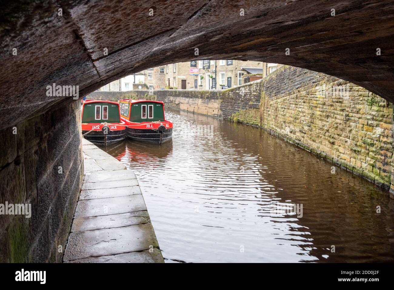 Rot und weiß lackierte schmale Boote unter einer Kanalbrücke auf dem Leeds und Liverpool Kanal in Skipton, North Yorkshire UK Stockfoto