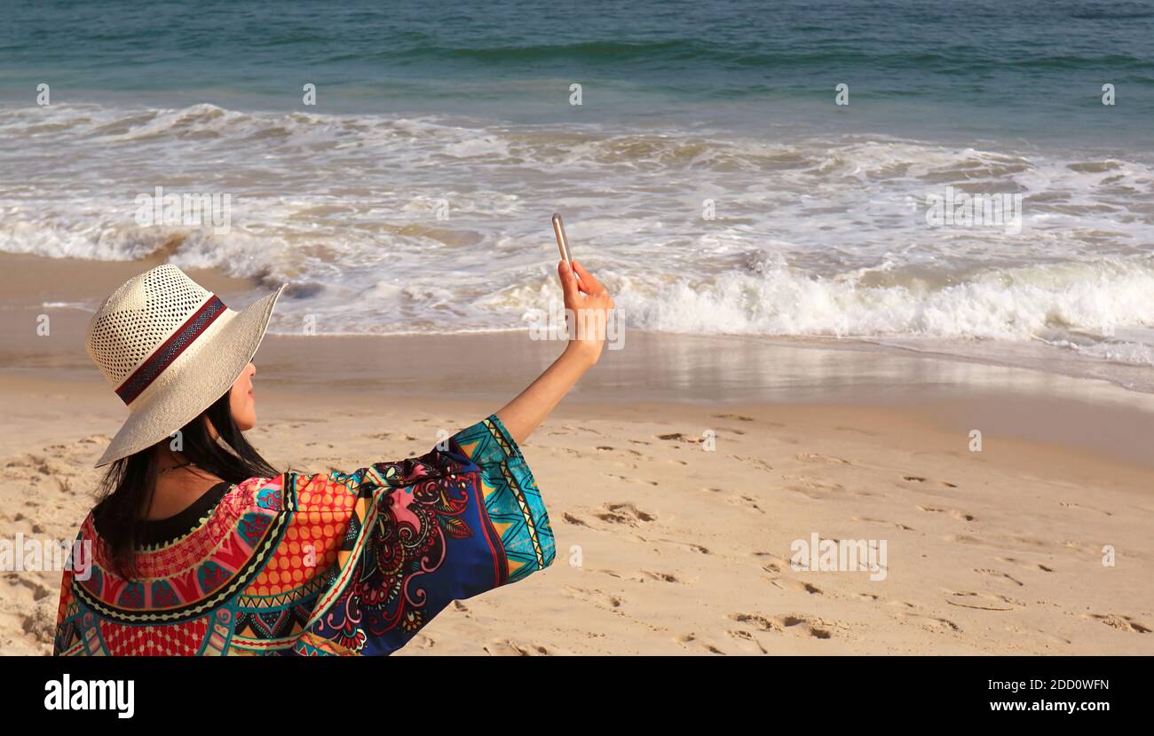 Frau in breiter Krempe hat genießen Sie die Aufnahme Selfie Bilder auf Der Wavy Beach Stockfoto