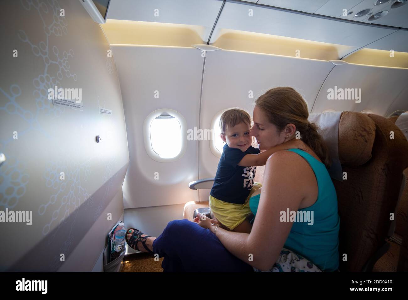 Reisen Sie mit einem Kind. Nettes Kleinkind Umarmungen Mama, während im Flugzeug Beifahrersitz sitzen Stockfoto