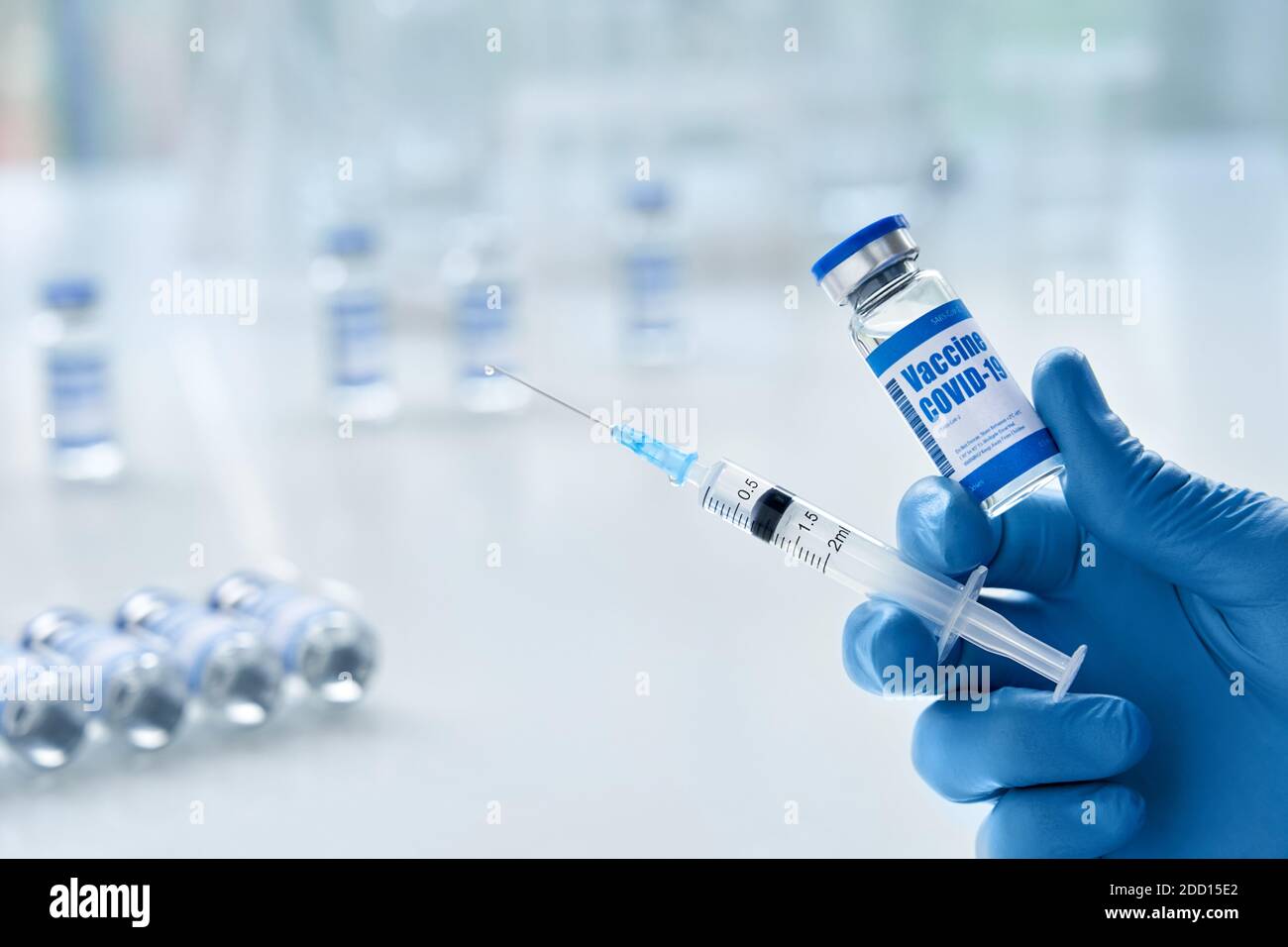 Männliche Arzthand trägt Handschuh hält Spritze und Fläschchen mit covid 19 Impfstoff. Stockfoto