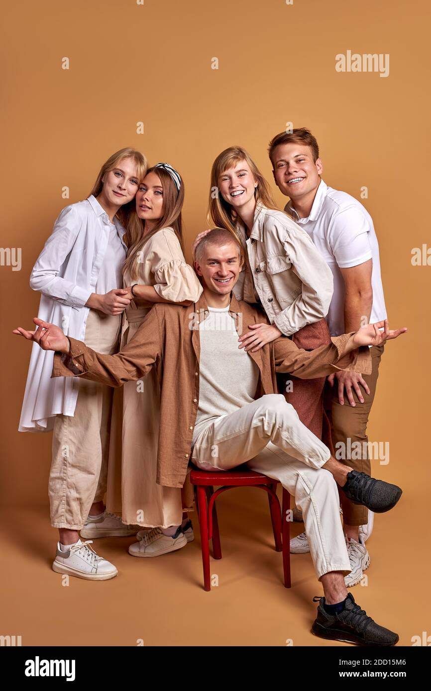 Portrait von trendy stilvolle Jugend posiert bei der Kamera isoliert auf braunem Hintergrund, gutaussehende männliche und schöne Frauen in modischen braunen Kleidung stehen zusammen, Modelle Stockfoto