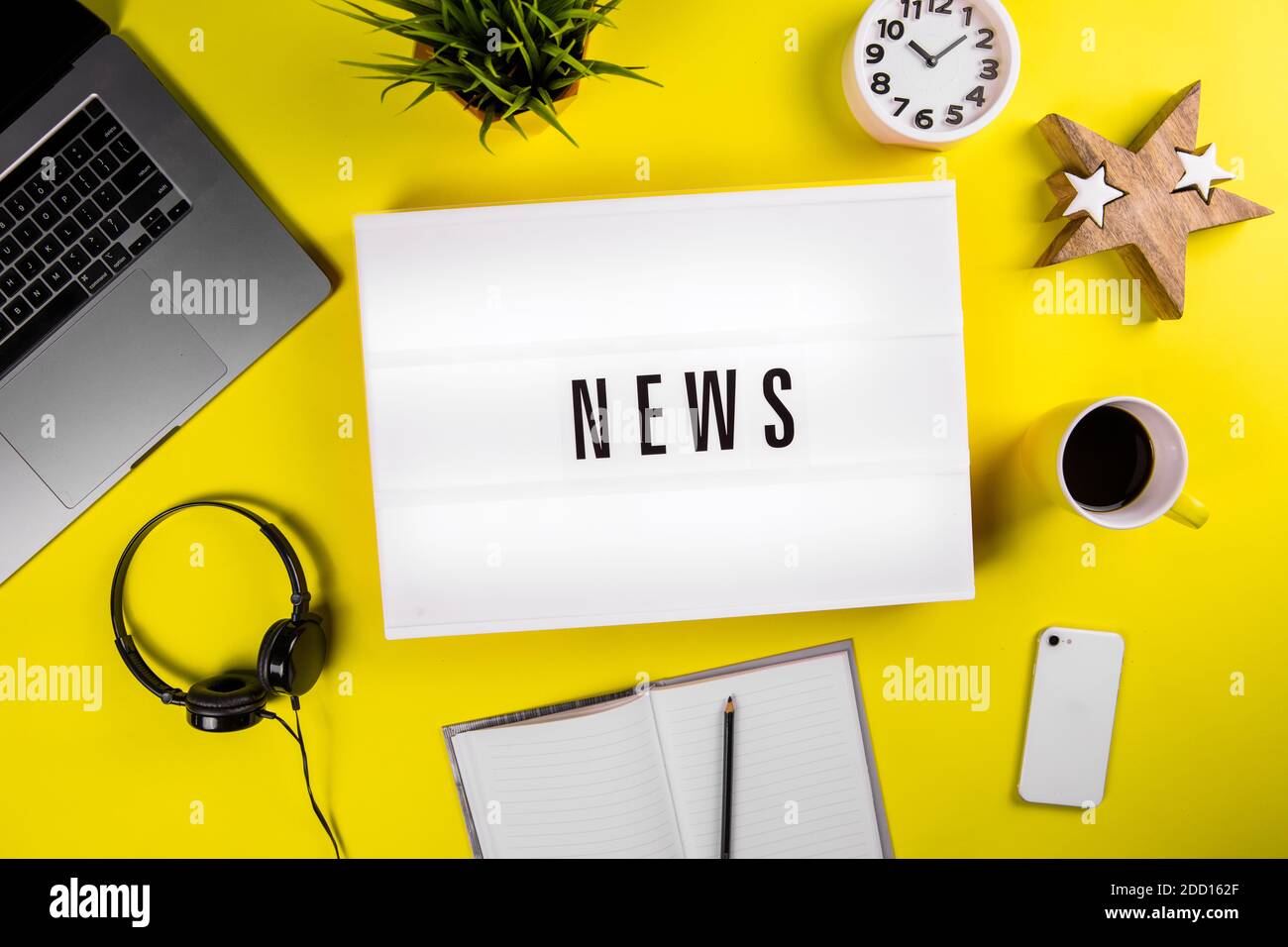 News Wort auf Leuchtkasten auf modernen gelben Büro-Desktop mit Laptop, Smartphone Stockfoto