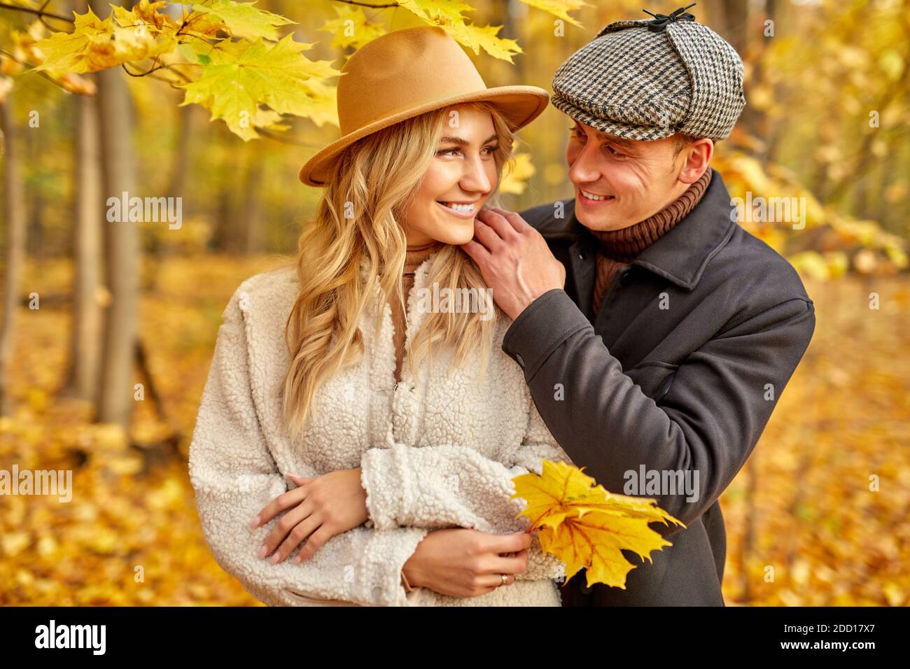 Glücklich kaukasischen Familienpaar genießen, im Herbst Natur, Liebe Konzept. Sie umarmen, blonde Frau in Hut halten gelben lassen in den Händen, posiert Stockfoto