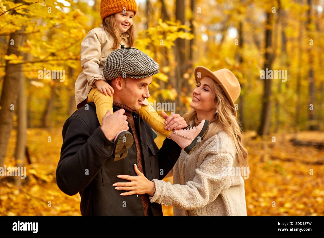Eltern und Kind gehen an einem sonnigen Herbsttag im Wald spazieren, posieren, lächeln und lachen, tragen warme Kleidung für kalte Tage Stockfoto Eltern und Kind gehen an einem sonnigen Herbsttag im Wald spazieren, posieren, lächeln und lachen, tragen warme Kleidung für kalte Tage Stockfoto