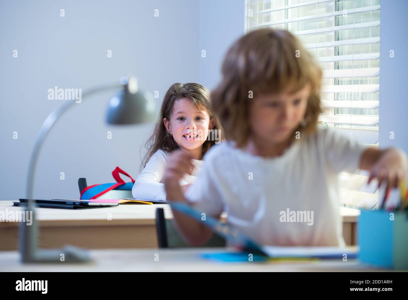 Kind im Klassenzimmer in der Schule. Junge und Mädchen sitzen am Schreibtisch und schreiben einen Text. Stockfoto