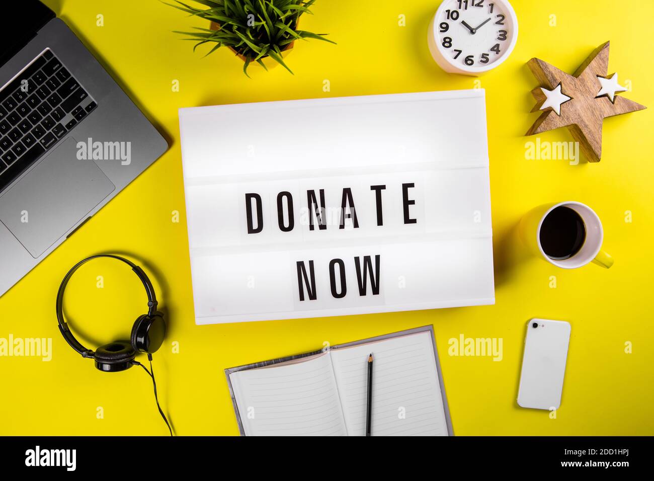 Spenden Sie jetzt Nachricht auf Leuchtkasten auf modernen gelben Büro-Desktop Mit Laptop Stockfoto