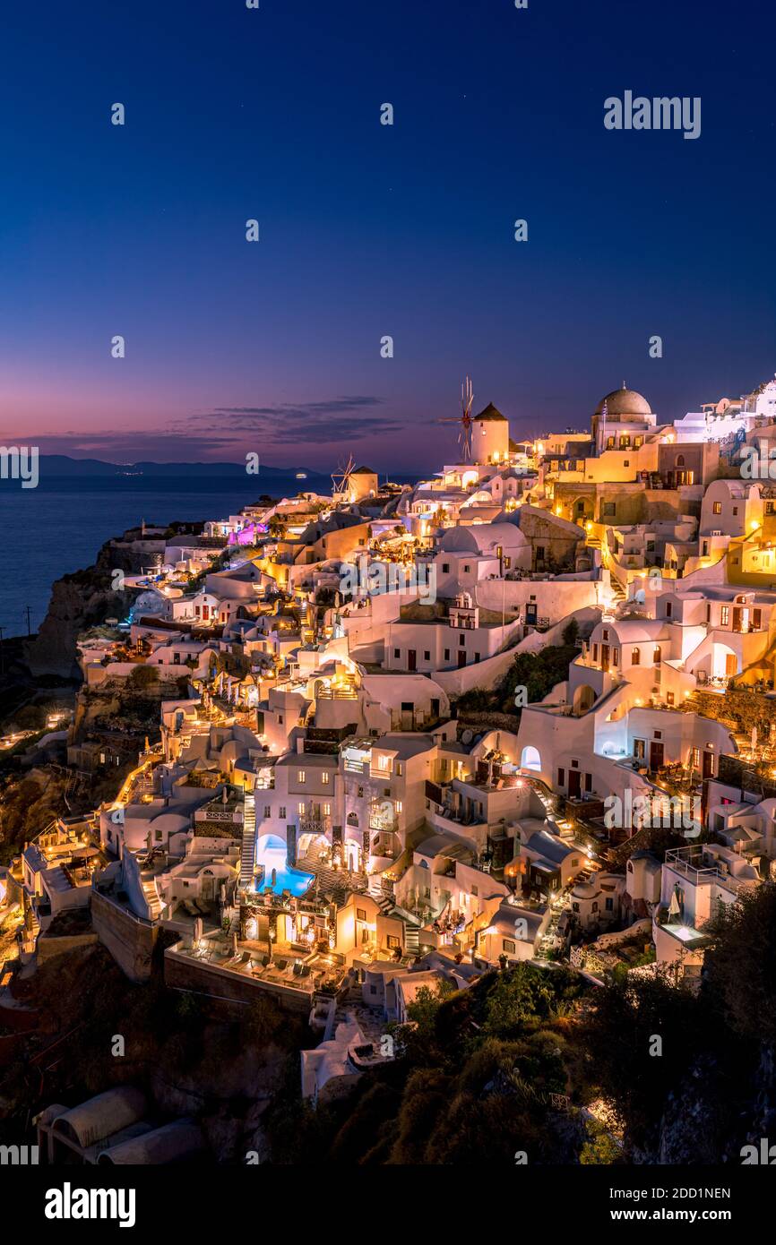 Atemberaubende Sonnenuntergangslandschaft. Schöne Aussicht auf fabelhafte Dorf Oia mit traditionellen weißen Häusern und Windmühlen in Santorini Insel bei Nacht, Griechenland Stockfoto
