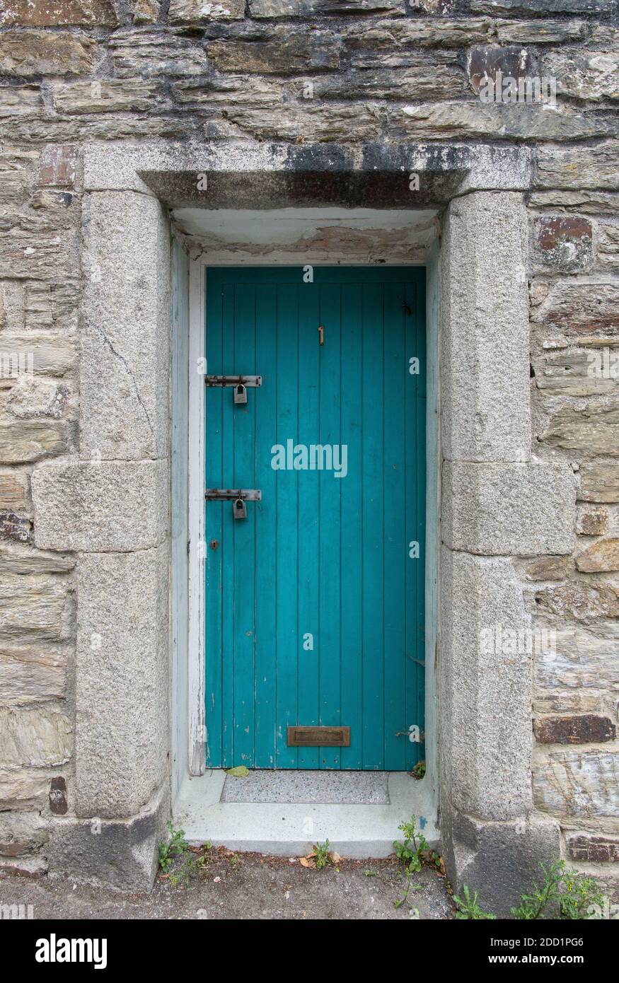 Eine blaue Holztür in einem Steinhaus in Fowey, England. Stockfoto