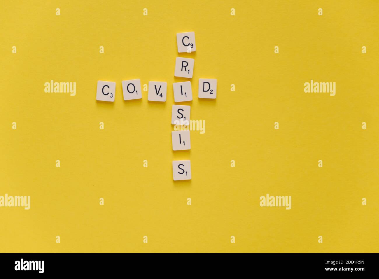 Covid-Krise. Wort Kreuzworträtsel Scrabble Spiel auf einem gelben Hintergrund. Speicherplatz kopieren. Stockfoto