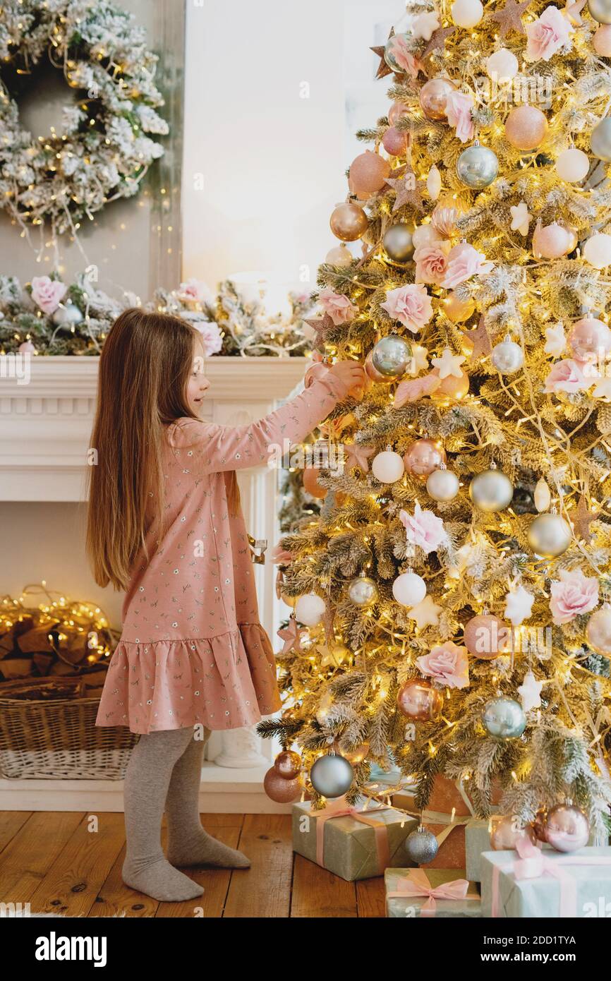 Nettes kleines Mädchen mit langen Haaren Dekoration Weihnachtsbaum zu Hause. Stockfoto
