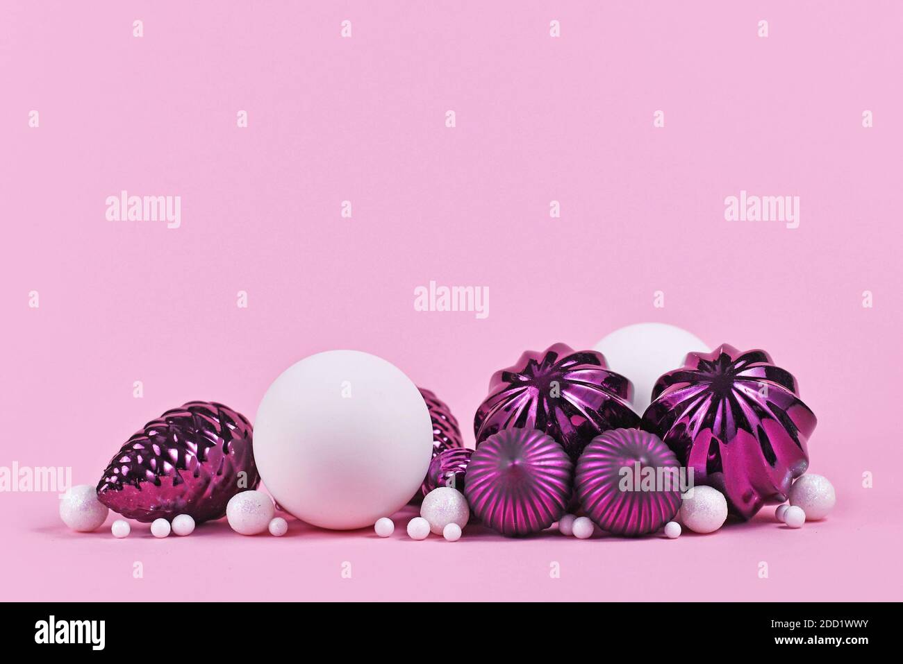 Weihnachtsarrangement mit lila und weißen Baumschmuck Glaskugeln Auf rosa Hintergrund mit leerem Kopierbereich Stockfoto