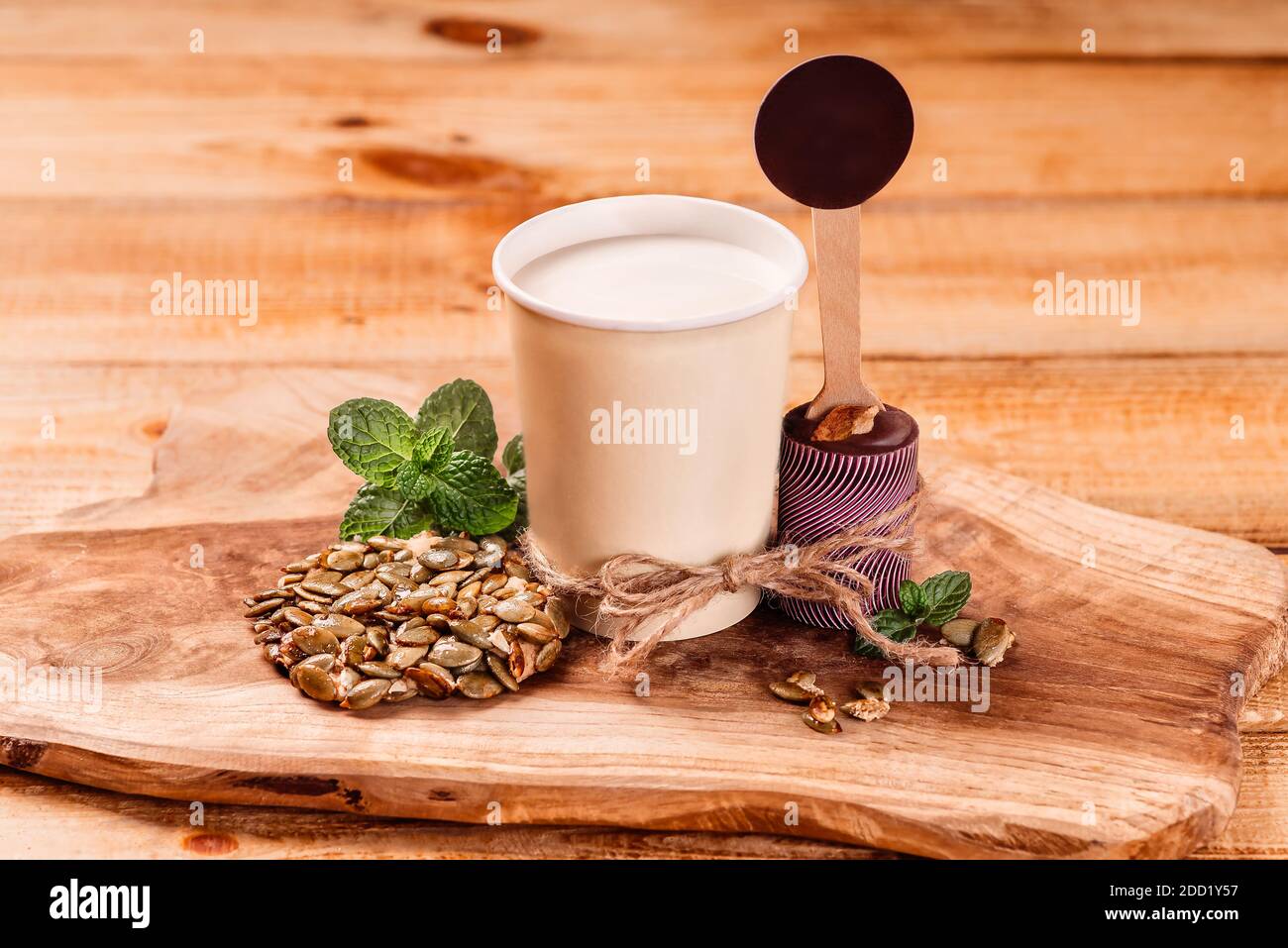 Milch in einer Tasse neben Schokolade auf einem Küchenschneidebrett auf einem hölzernen Hintergrund. Stockfoto