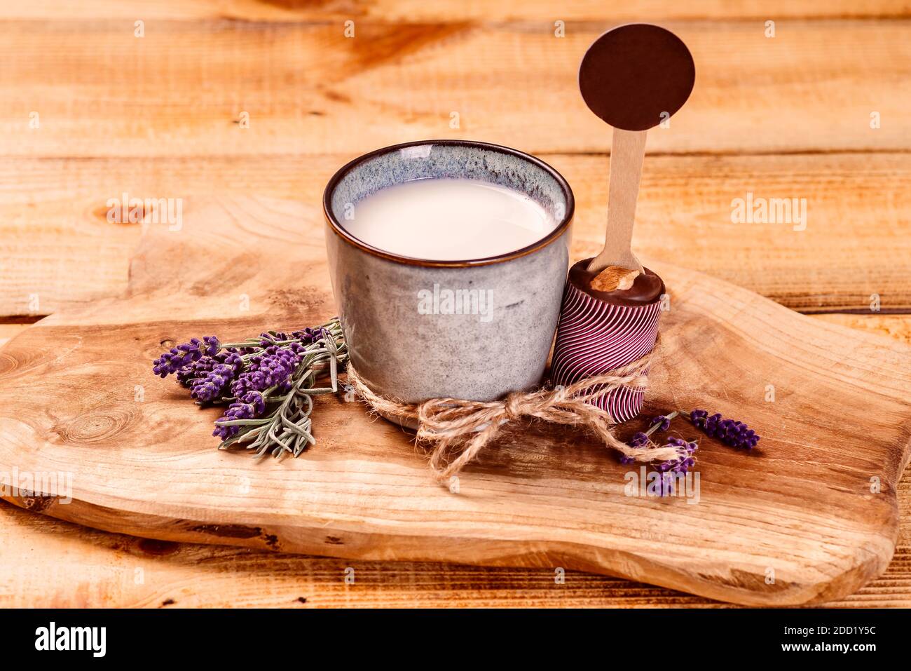 Milch in einer Tasse neben Schokolade auf einem Küchenschneidebrett auf einem hölzernen Hintergrund. Stockfoto