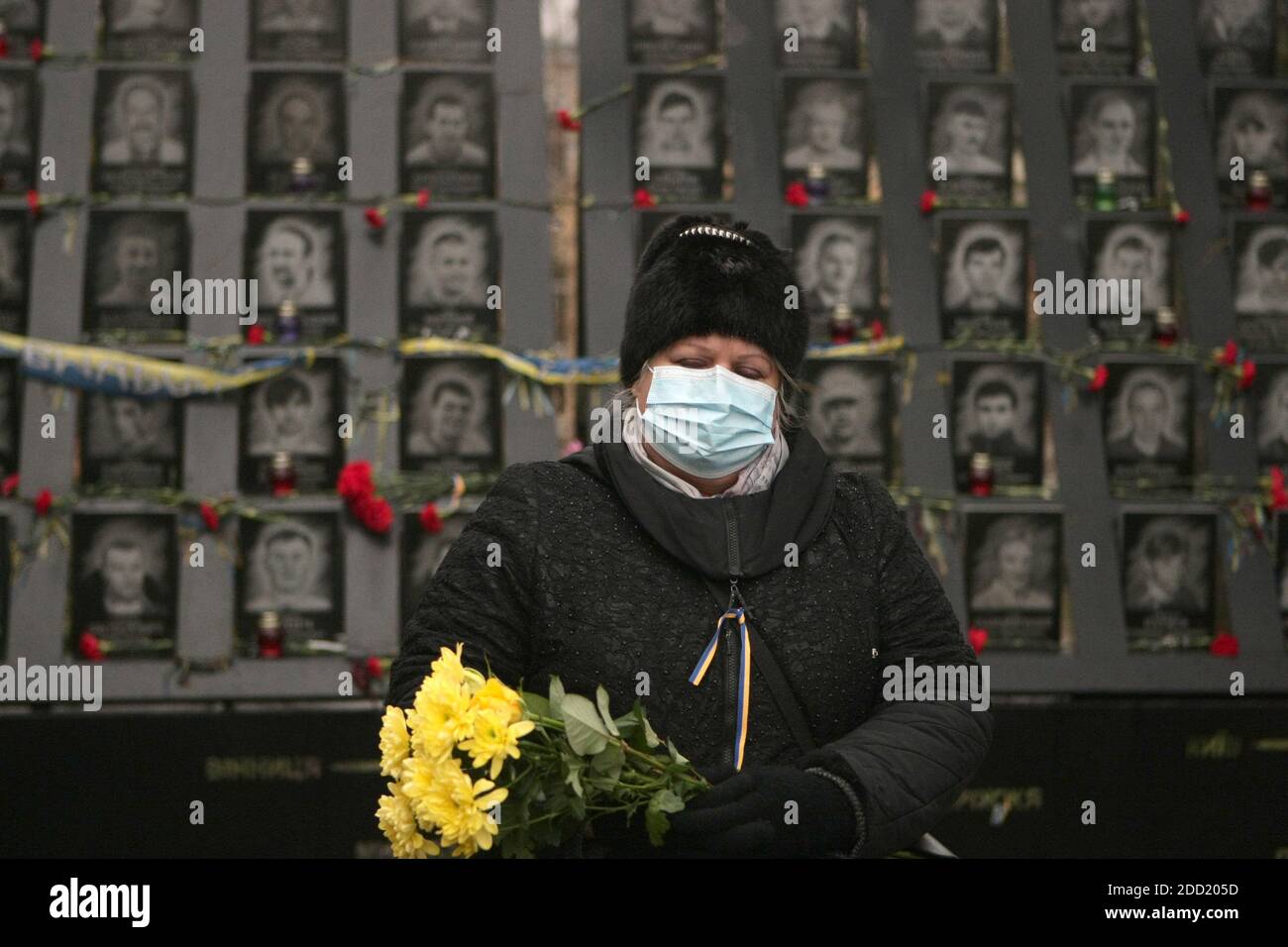 Nicht exklusiv: KIEW, UKRAINE - 21. NOVEMBER 2020 - EINE Frau mit Blumenstrauß zollt den Himmlischen Hundert Helden am Tag der Freiheit und des Dignits Tribut Stockfoto