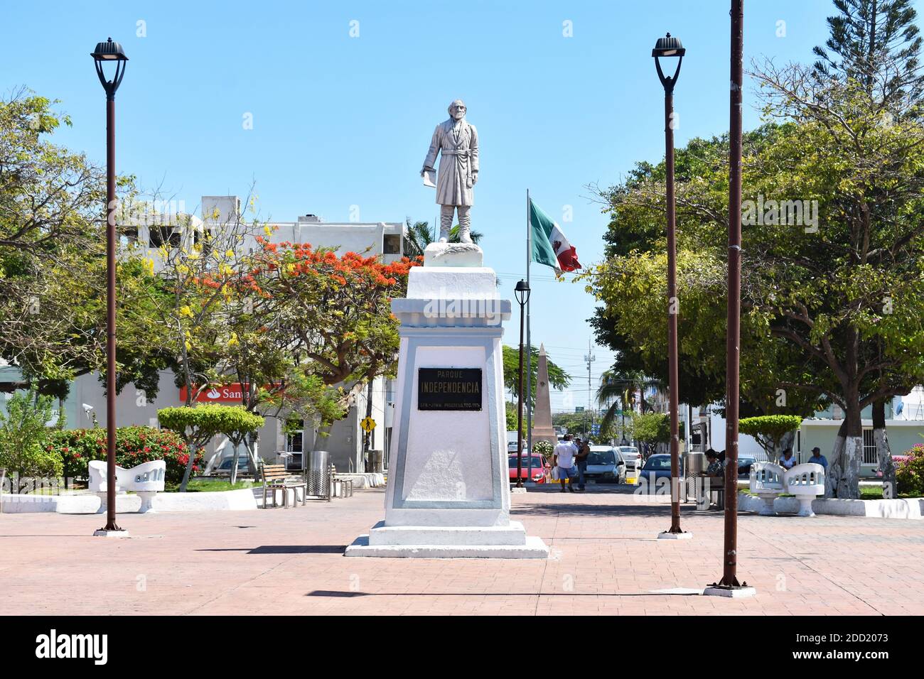 Independence Park in Progreso, Yucatan Peninsular, Mexiko. Eine große Statue steht in der Mitte und eine mexikanische Flagge fliegt im Hintergrund. Stockfoto