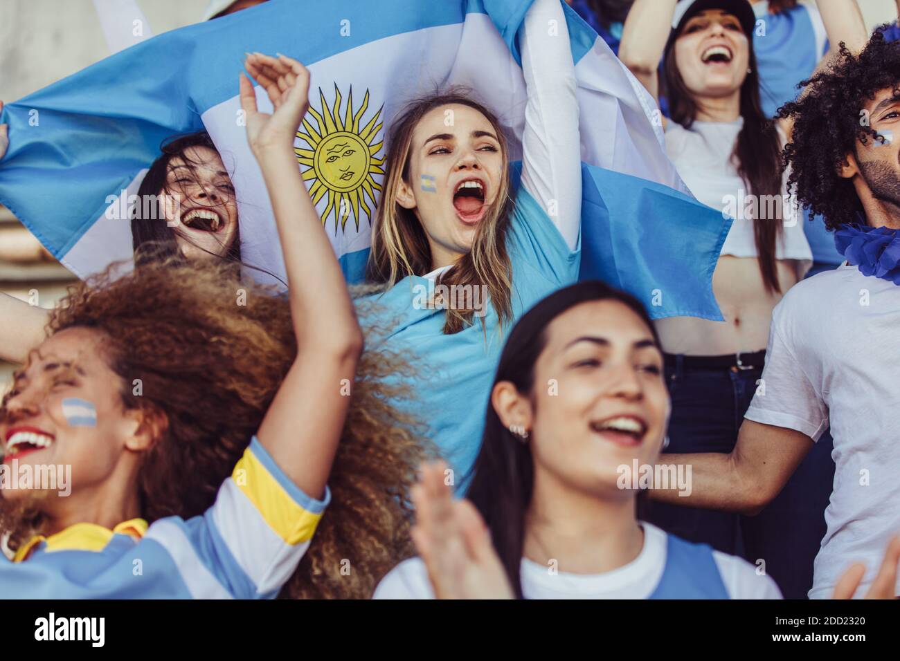 Frauen im Stadion mit einer argentinischen Flagge jubeln ihr Team. Frauen aus Argentinien in Fanzone genießen während einer Sportveranstaltung. Stockfoto