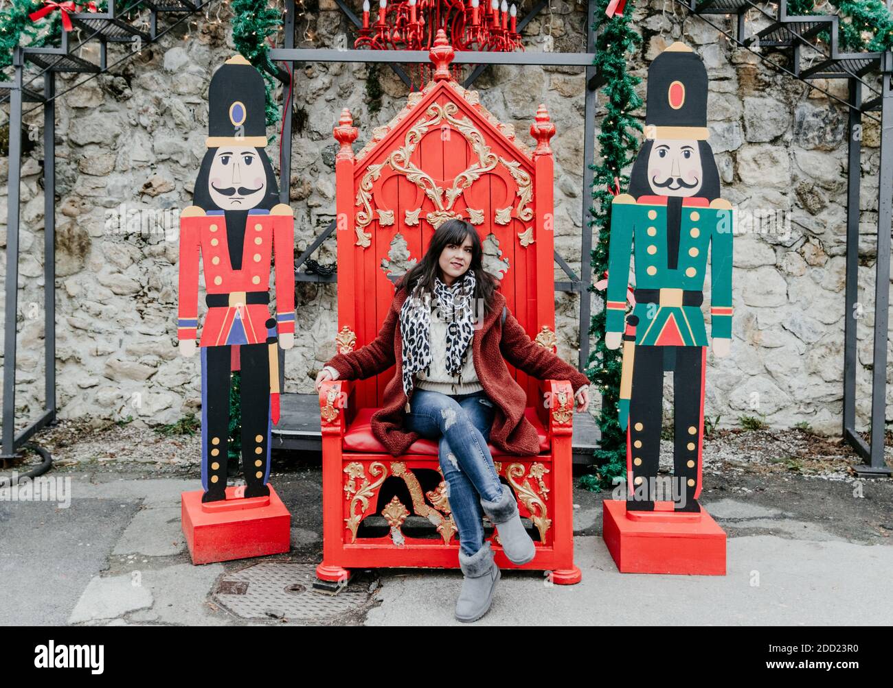 Ein Porträt einer jungen kaukasischen Frau, die auf einem sitzt Roter Stuhl inmitten der Dekoration Stockfoto