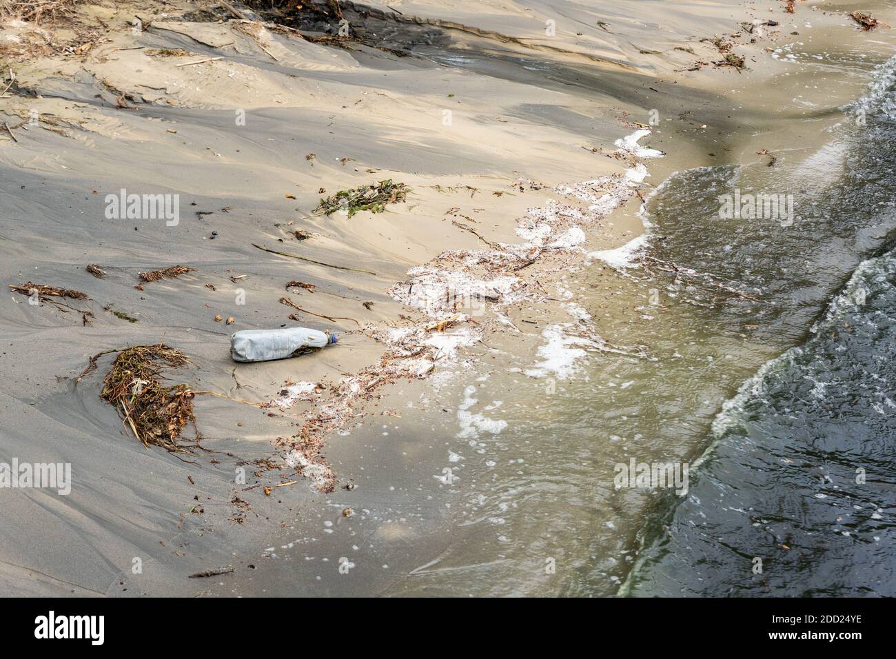 Sand Meer oder See Strand verschmutzt mit Plastikflaschen und schwarzen schädlichen giftigen Abwasserchemikalien. Natur kontaminiert mit Industriefabrik oder Anlage Stockfoto
