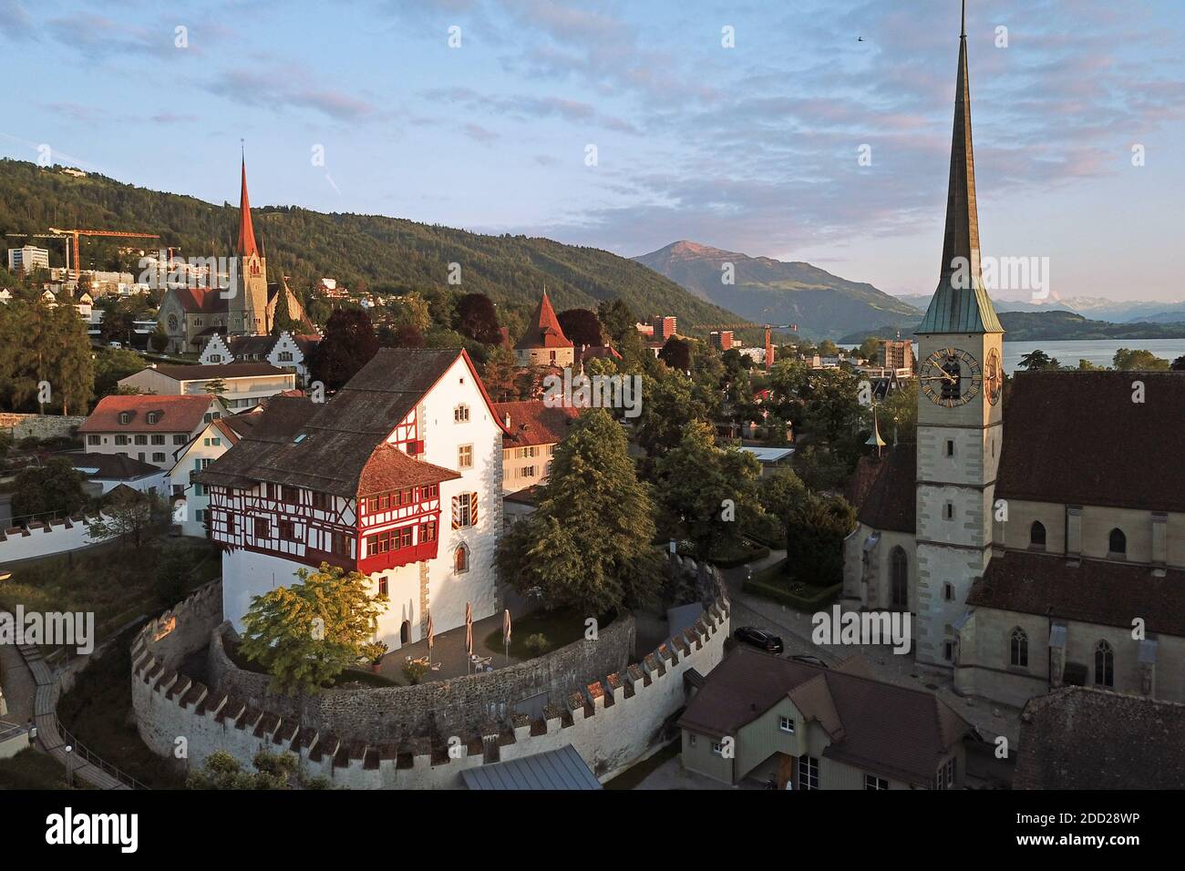 Luftdrohnenaufnahme von Zug, Schweiz mit Fokus auf Schloss Zug, Katholische Kirche St. Oswald und St. Michel weiter im Hintergrund. Stockfoto