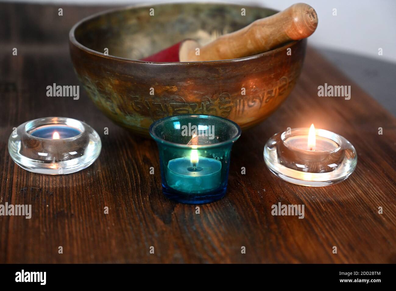 Eine tibetische Klangschale mit brennenden Kerzen auf einem Holz Tabelle Stockfoto