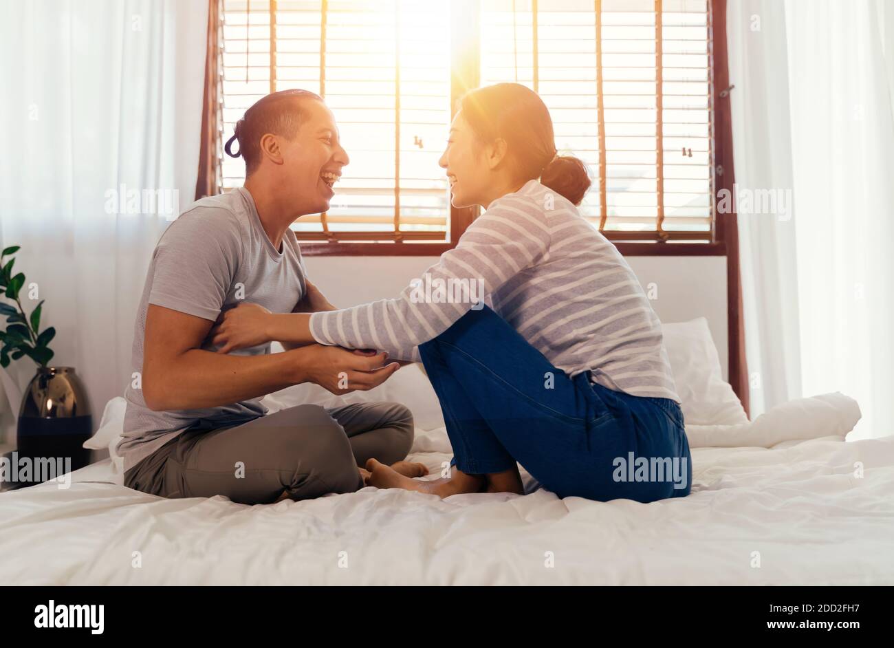 Portrait von glücklich junge Erwachsene asiatische Paar kitzelt sich gegenseitig auf dem Bett zusammen im Schlafzimmer Innenleben Szene. 30s offen reifen Mann und Frau lächeln. Ehe und glückliche Beziehung Leben Konzept. Stockfoto
