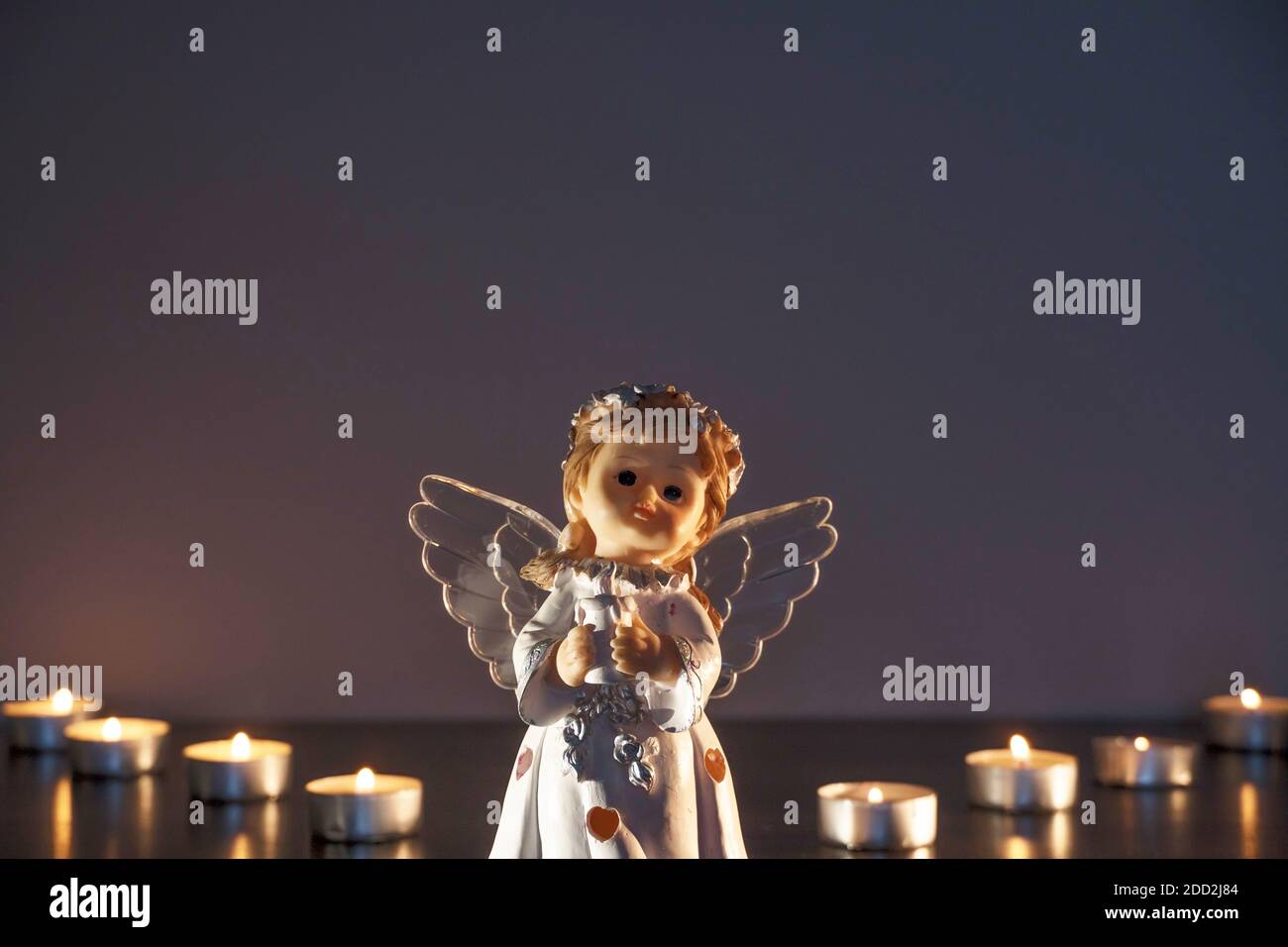 Weißer Weihnachtsengel mit brennenden Kerzen in der Kirche. Spirituelle Gottheit in der Religion. Stockfoto