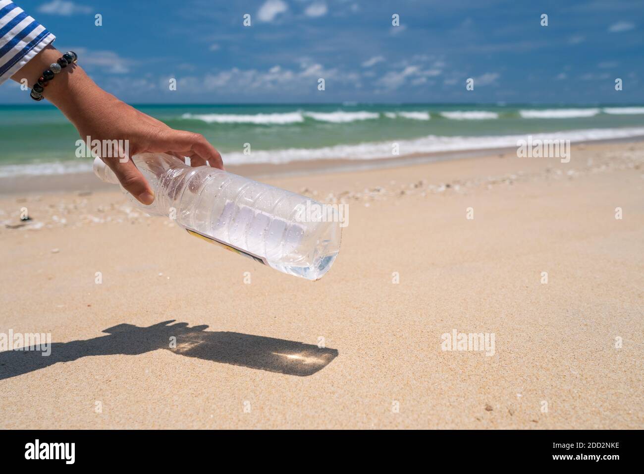 Holen Sie sich am wunderschönen Strand leere Wasserflaschen oder Müll mit der Hand. Umwelt Problem der globalen Erwärmung. Stockfoto