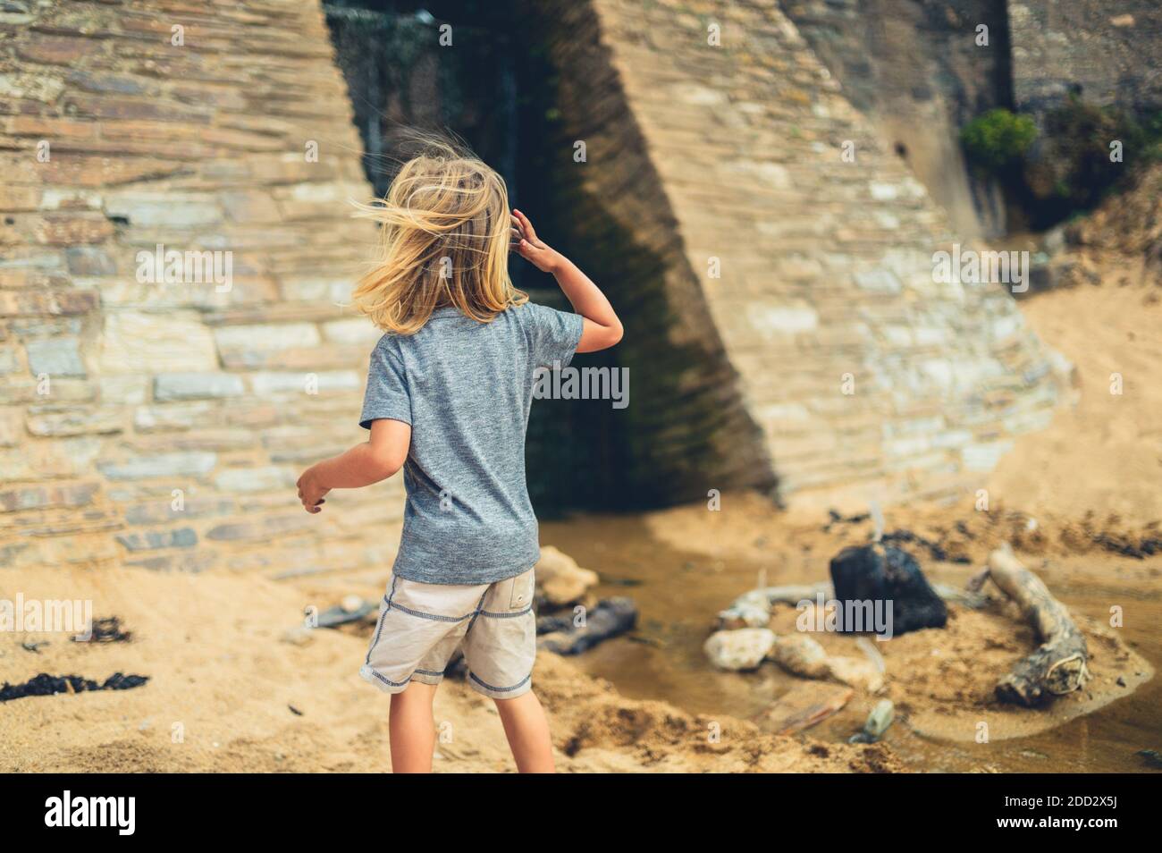 Ein kleiner Vorschulkinder spielt am Strand bei an Bewässerungskanal Stockfoto