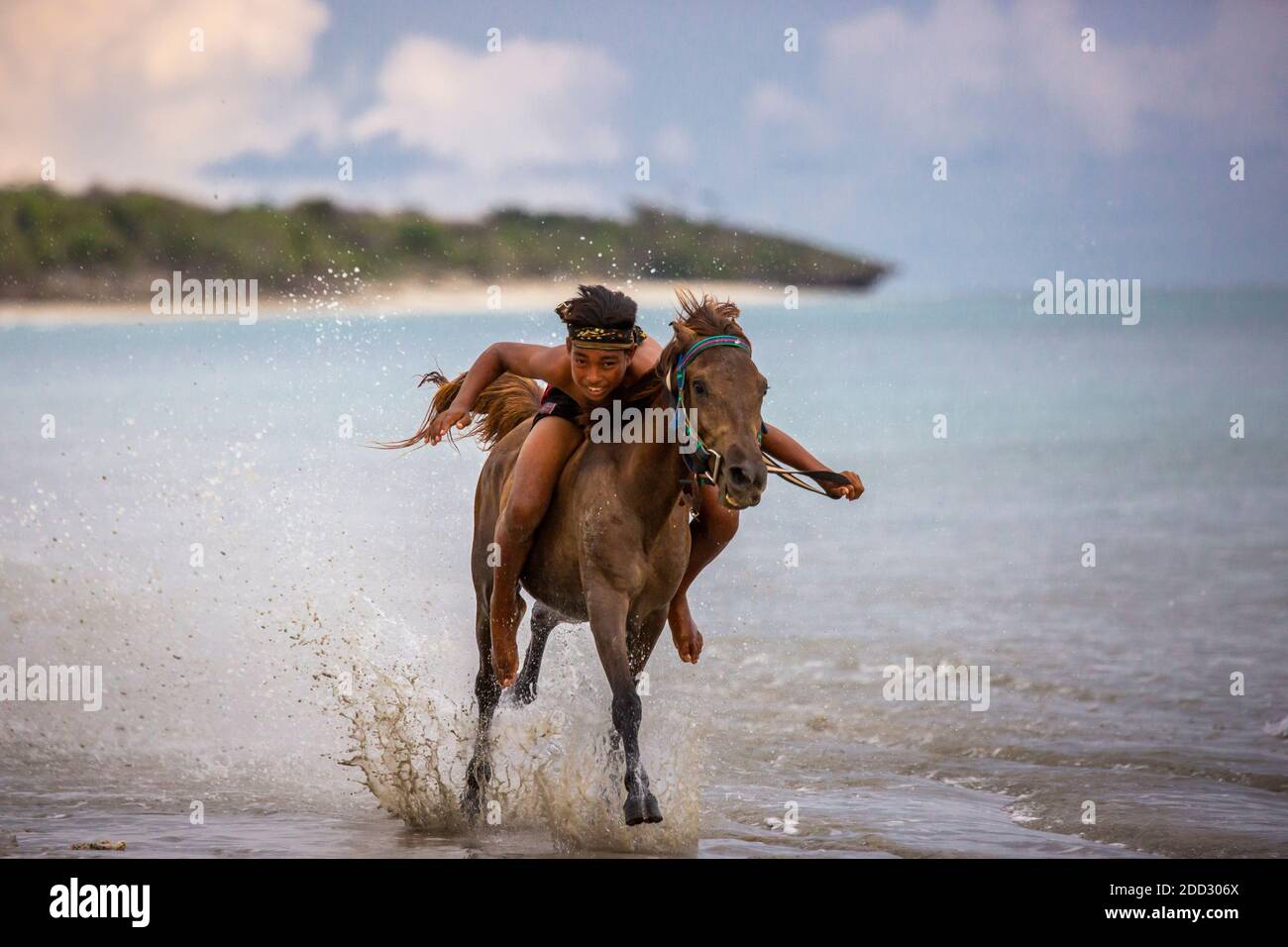 Ein sumbanesischer Joki Cilik oder kleiner Jockey spornt sein Sandalwood Pony während eines Mock Pferderennens am Mamboro Beach an. Stockfoto
