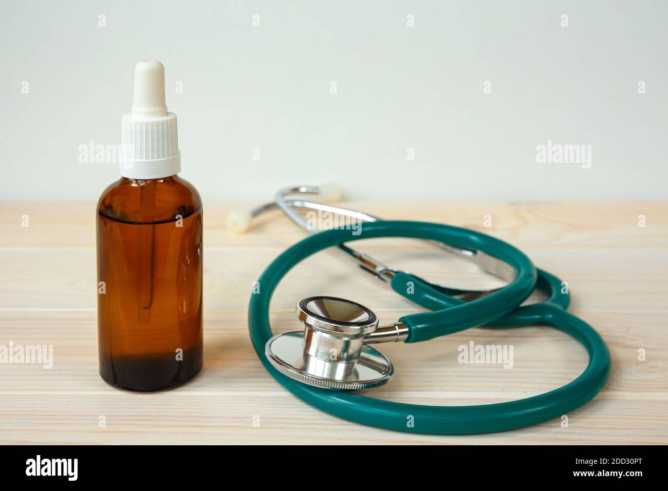Flasche aromatisches Öl oder Medizin und Stethoskop auf einem Weißer Holztisch Stockfoto