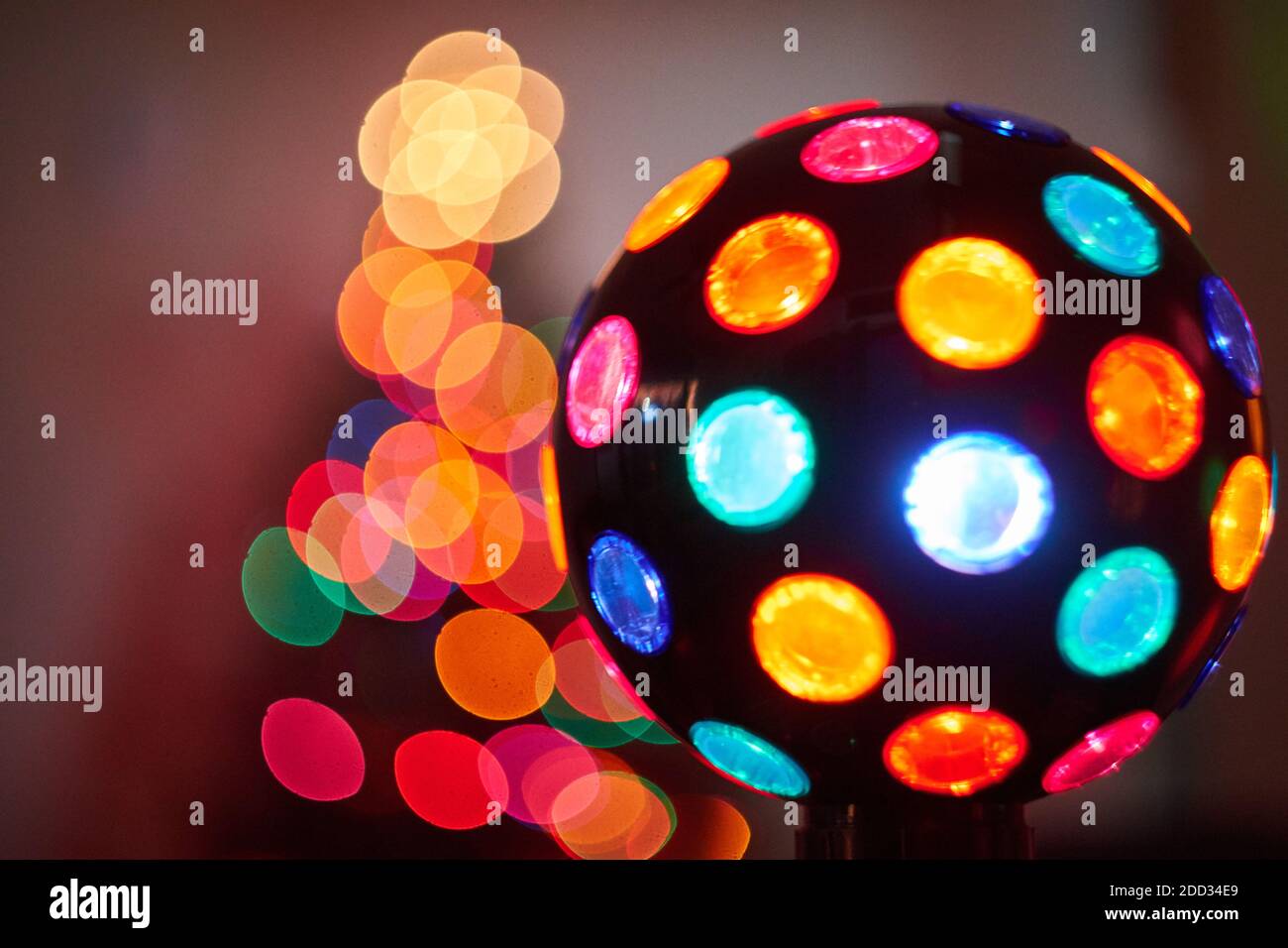Bunte Disco Ball Dekoration vor verschwommenem Weihnachtsbaum drinnen. Stockfoto