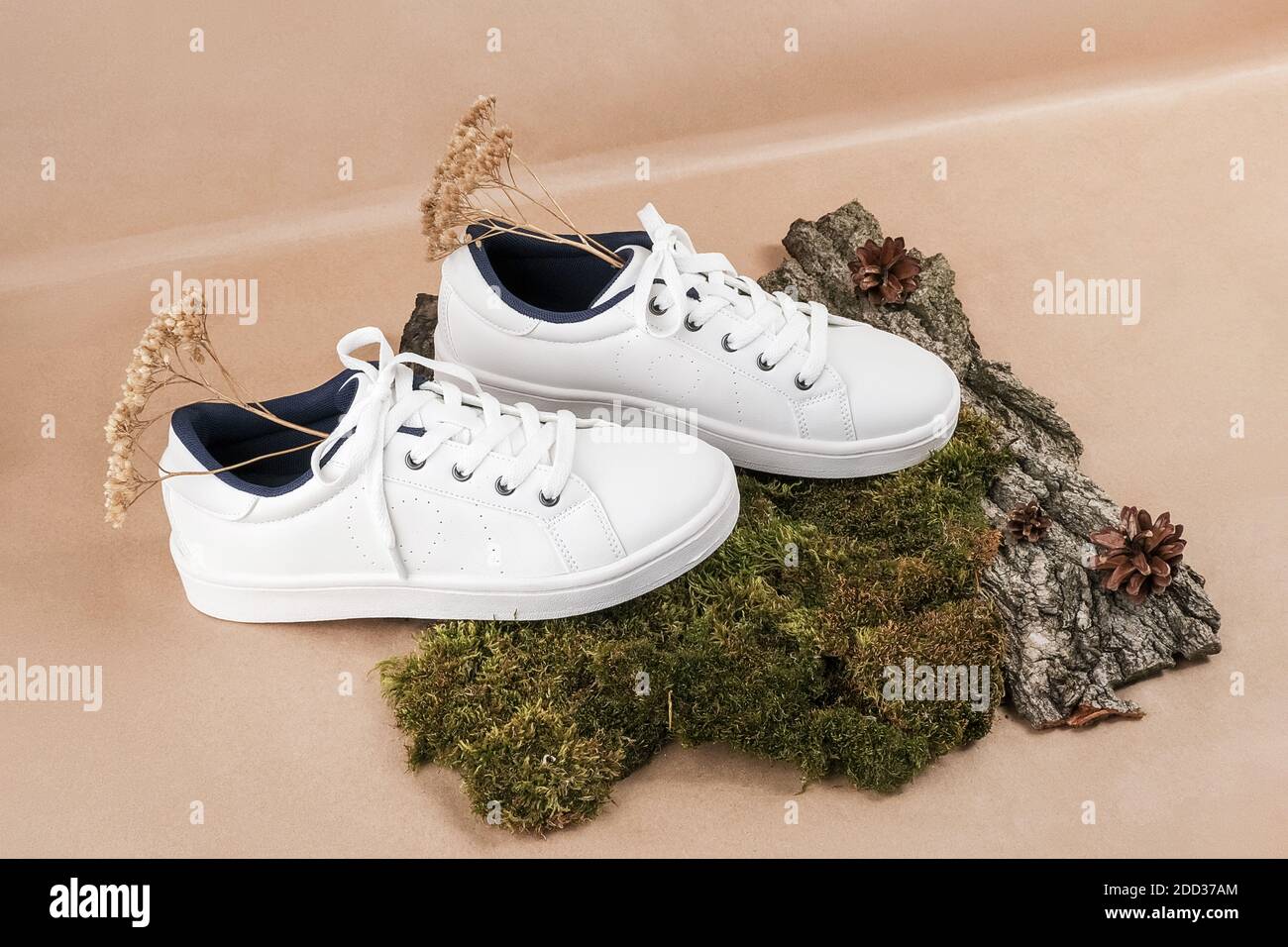 Ethisches veganes Schuhkonzept. Ein Paar weiße Sneakers mit trockenen Blumen  auf Baumrinde und Moos, neutral beige Bastelpapier Hintergrund  Stockfotografie - Alamy